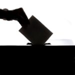 hand placing ballot into box